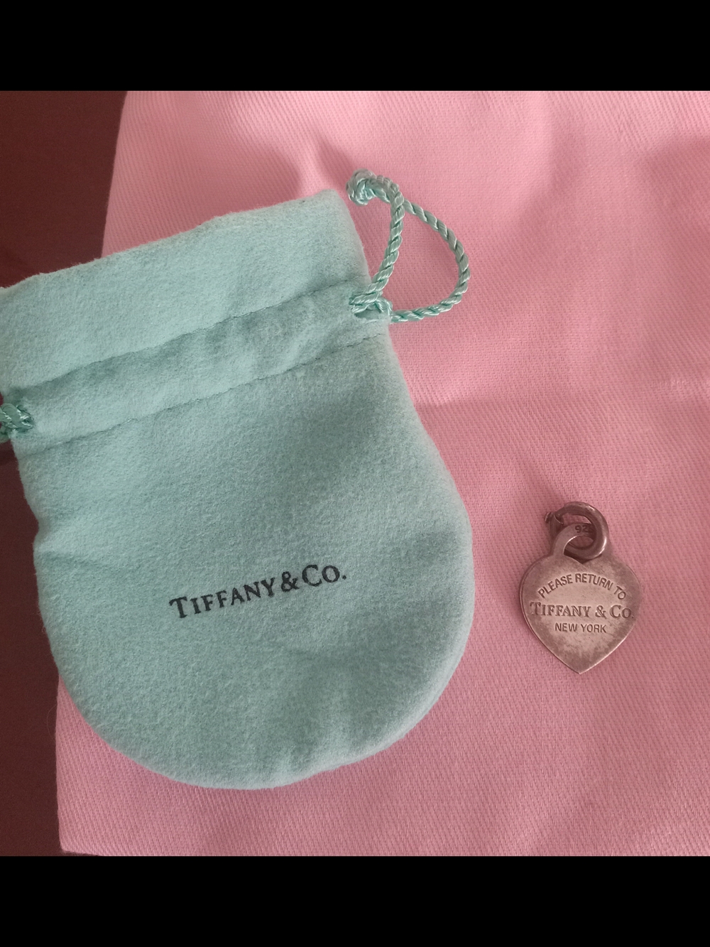 Tiffany & Co. Heart Tag Charm with Tiffany Blue Pouch on Pink Background